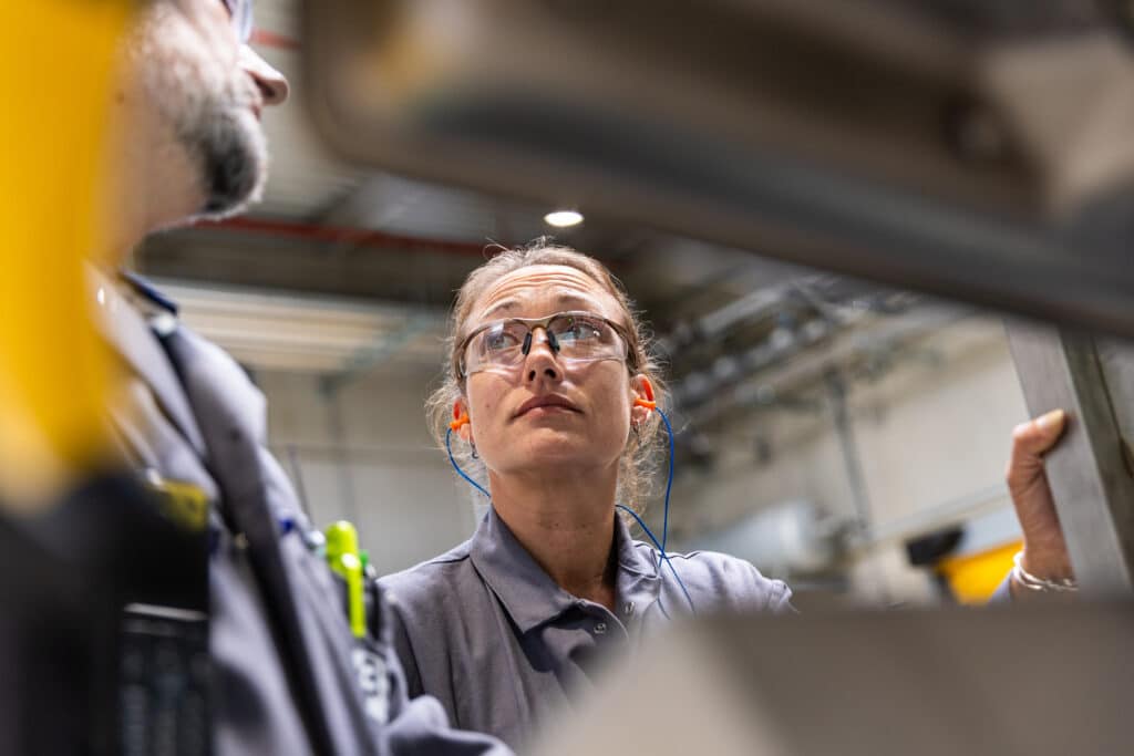Workers handling industrial equipment inside a manufacturing facility